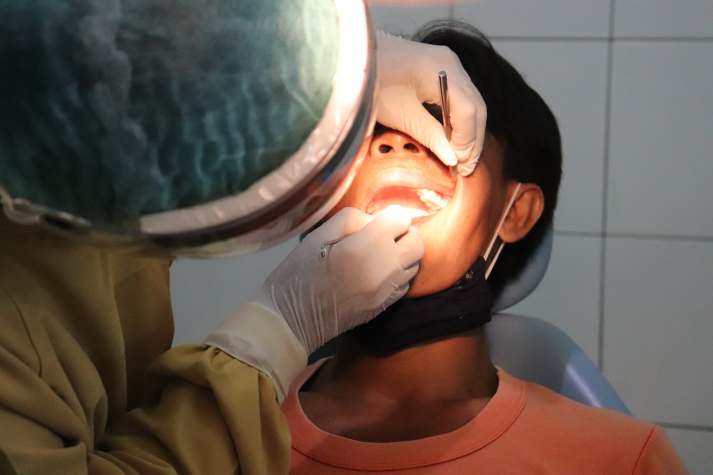 Dentist examining a patient's open mouth with instruments.