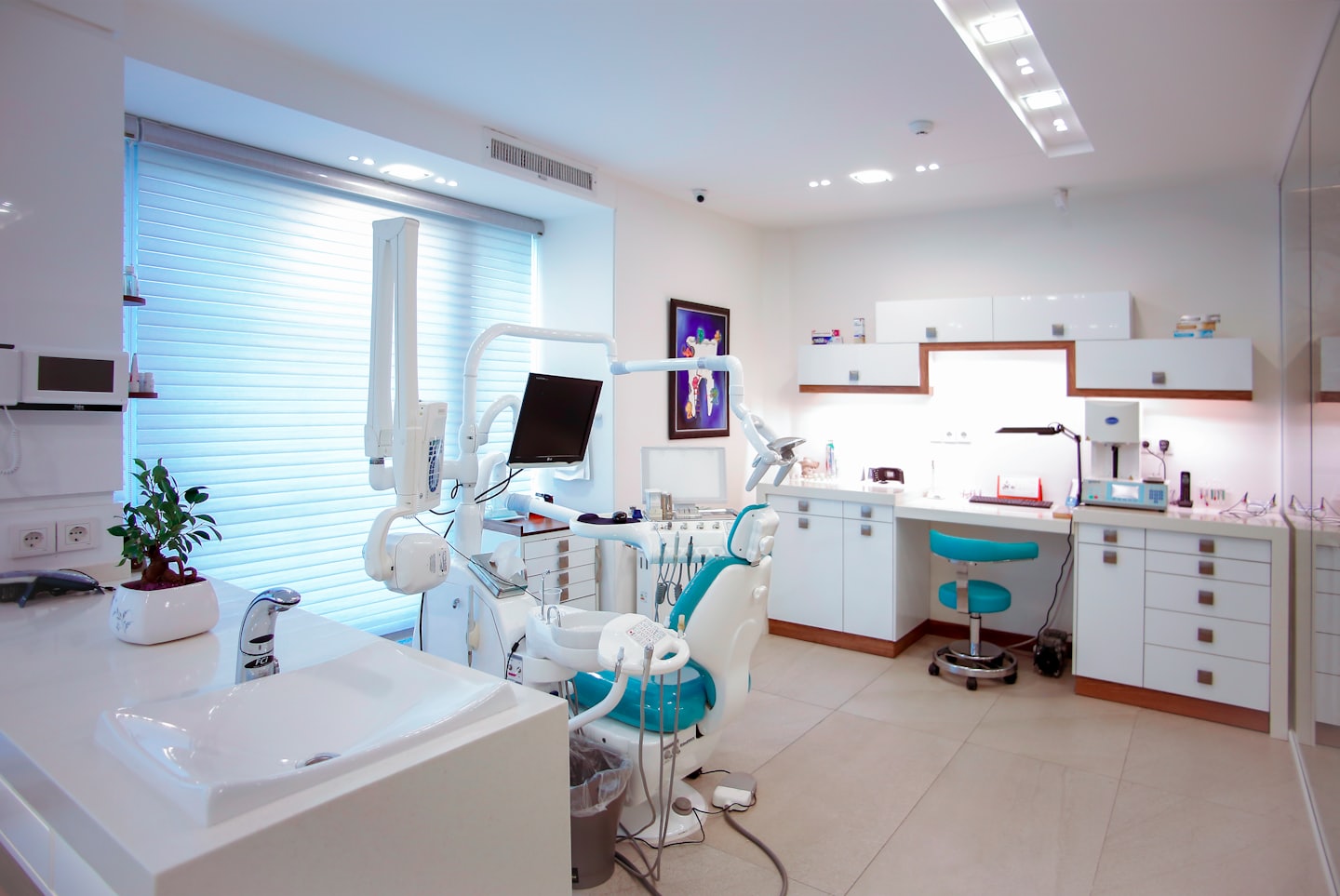 Modern dental office with a teal dental chair and equipment.