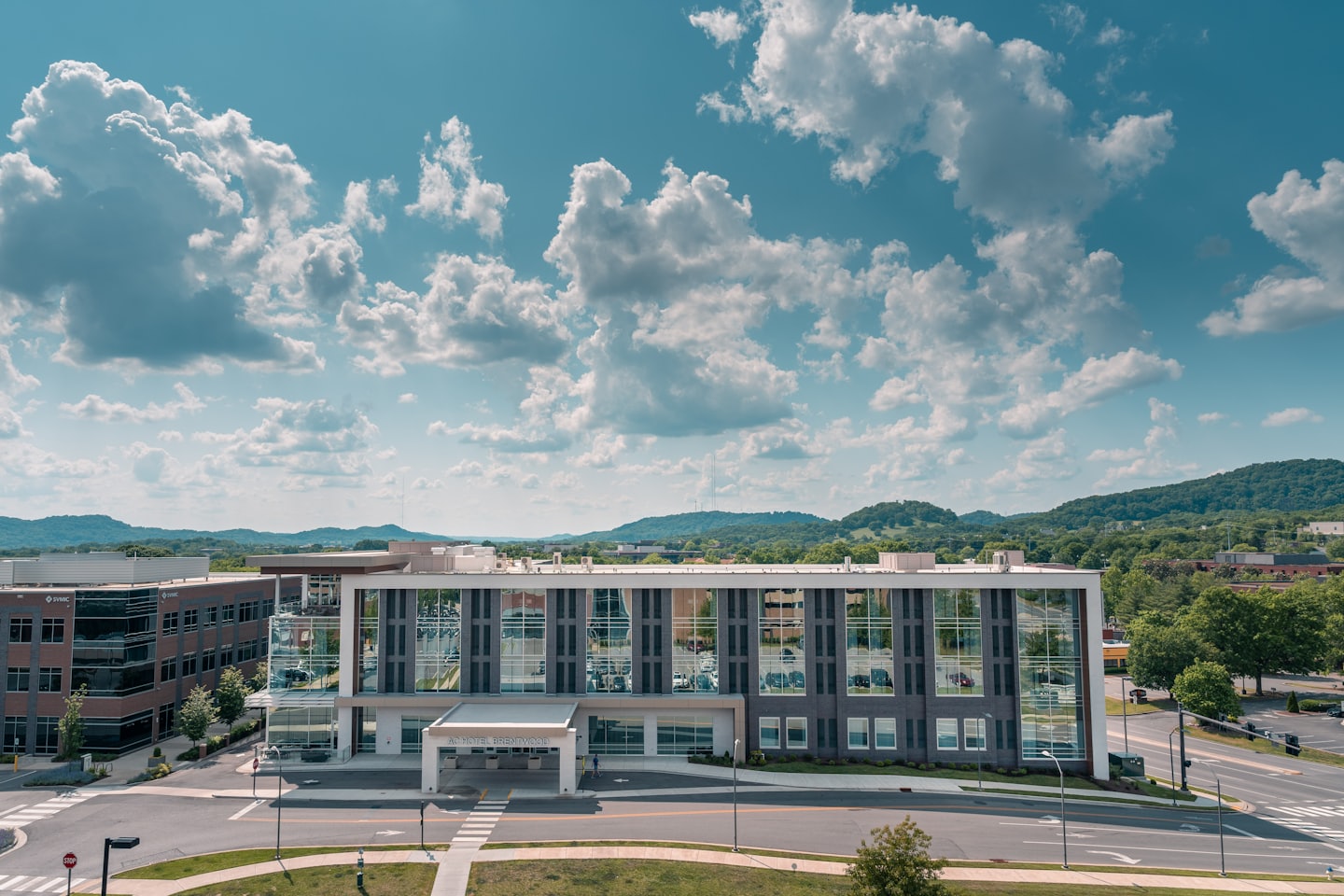 Modern medical facility building with glass windows near green hills.