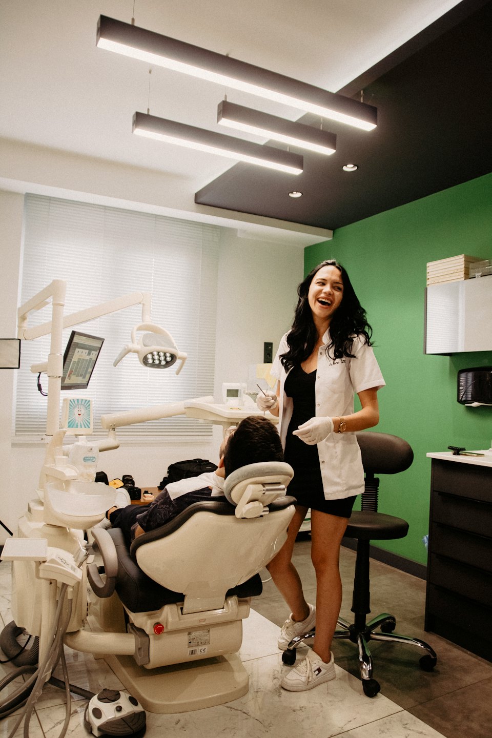 Female dentist laughs with patient in a bright, modern dental office.